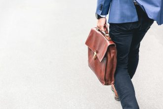 person walking holding brown leather bag; job loss