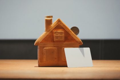 A small house bank with a coin and blank card.