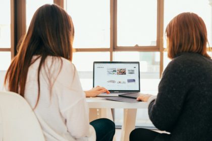 two women talking while looking at laptop computer; client