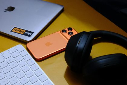 Laptop, phone, keyboard, and headphones on yellow surface; Communication Tools