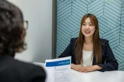 a woman sitting at a table with a piece of paper in front of her; First Employee