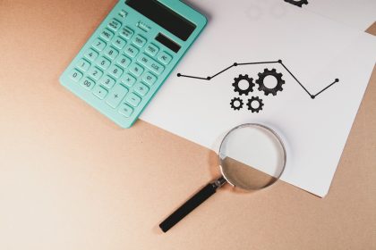 Calculator, magnifying glass, and chart with gears on paper.; ESG Data Streams