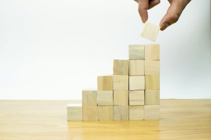 A person placing a piece of wood into a pyramid in their solo business.