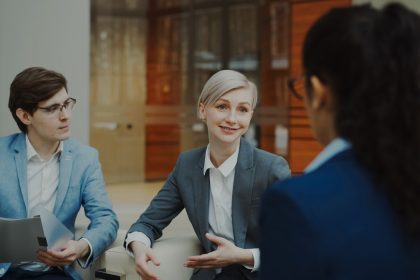 Three people in a business meeting discussing documents; negotiate freelance rates