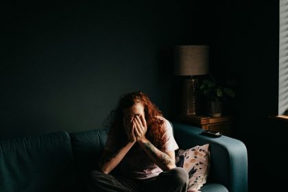 woman in black and white floral shirt sitting on black couch; self doubt