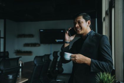 smiling man holding cup and using smartphone; thriving freelancers