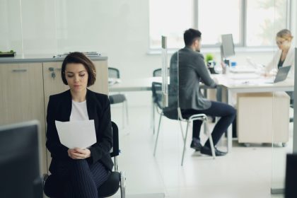 Woman sitting in office holding papers; hiring first employee
