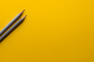 two gray pencils on yellow surface; brand in the age of ai