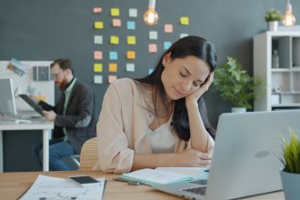 Woman resting head on hand at desk; boring businesses
