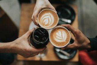 three person holding beverage cups; third place