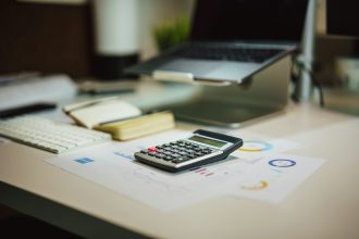 a calculator sitting on top of a table next to a laptop; tax deduction examples