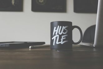black and white Hustle-printed ceramic mug on table; hustle is not enough