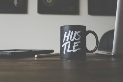 black and white Hustle-printed ceramic mug on table; hustle is not enough