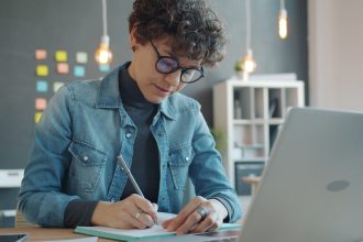 Woman with glasses writing in notebook at desk; slow season projects