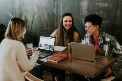 three people sitting in front of table laughing together; how to get freelance clients