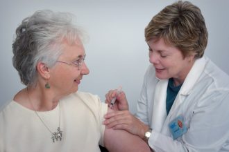 woman inject a woman on left shoulder; online nurse practitioner program