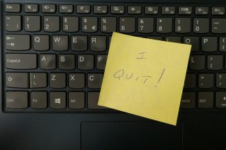 a yellow notepad on a keyboard; feel like quitting