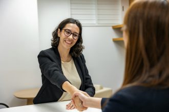 a woman shaking hands with another woman sitting at a table; hiring your first team member