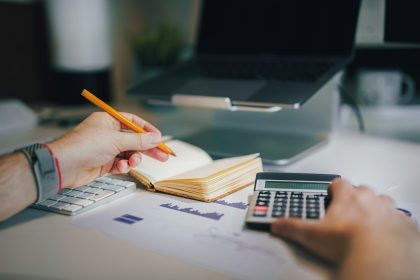 a person sitting at a desk with a calculator and a notebook; independent contractor taxes