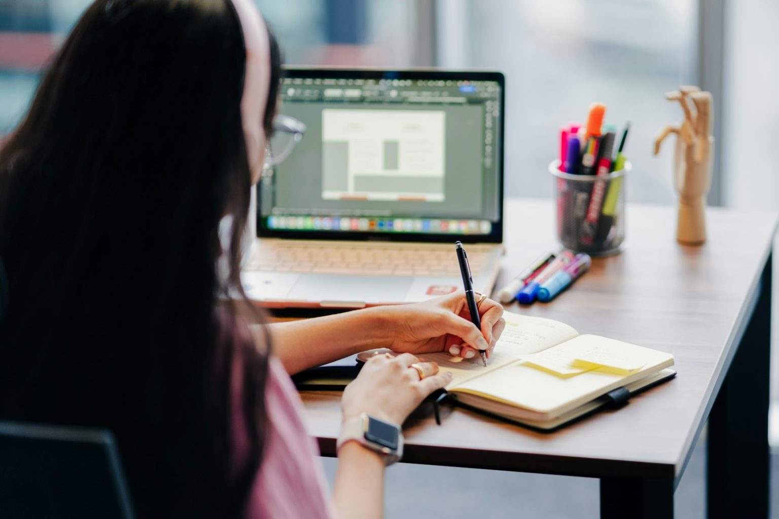 Woman working at a desk with laptop and notebook; 1099 employee