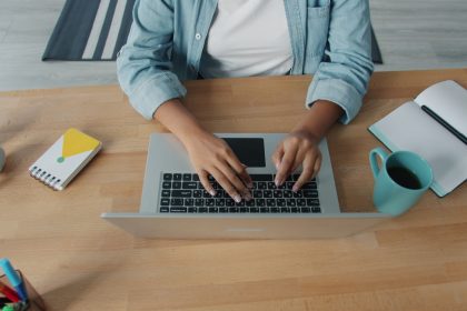 Person typing on a laptop at a wooden desk.; mastering freelance schedules