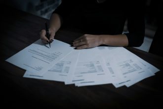 a woman sitting at a table with lots of papers; taxes