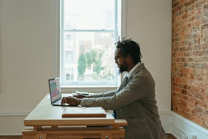 a person sitting at a desk with a laptop and papers; sole proprietorship