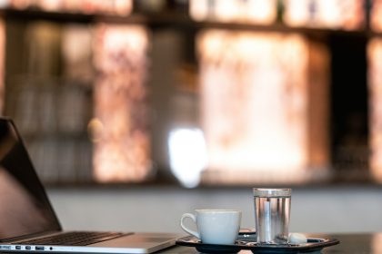 Laptop, coffee, and water sit on a table; HSA self-employed