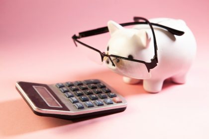 A piggy bank wearing glasses next to a calculator; section 179 deduction self-employed