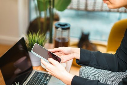 Person using a smartphone while working on a laptop.; Upwork ChatGPT integration