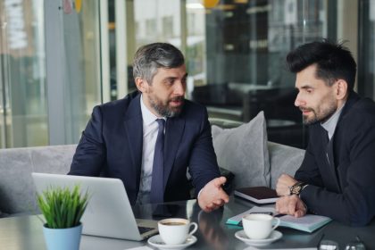 a couple of men sitting at a table in front of a laptop; how to start a consulting business