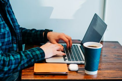 person wearing blue and green plaid collared button-up long-sleeved shirt sitting while using MacBook Pro; freelance website