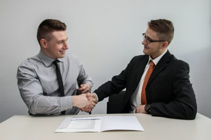 two men facing each other while shake hands and smiling; employers hiring freelancers 2026
