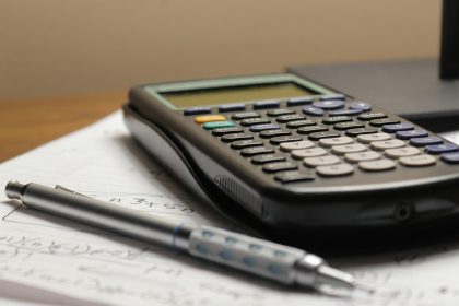 a calculator and a pen sitting on top of a piece of paper; schedule C