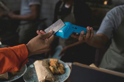 a person holding a blue object in their hand; credit card reader