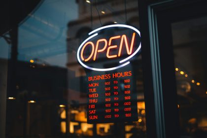 a neon sign that says open in front of a window; how much does it cost to start an llc
