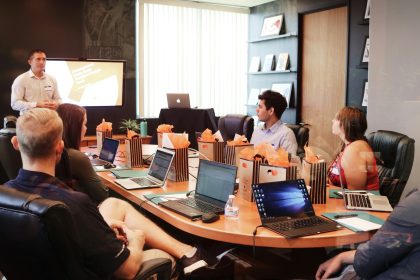 man standing in front of people sitting beside table with laptop computers; small business succession planning