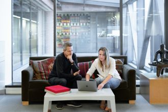 man and woman sitting on couch using macbook; cheapest registered agent