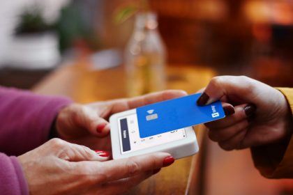 a person holding a credit card and a cell phone; credit card processing for small business