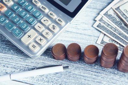 a calculator, pen, and money on a table; self-employment tax credit scam
