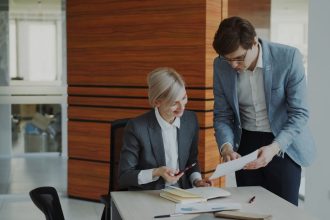 Two colleagues discussing documents at an office desk.; low-cost liability insurance
