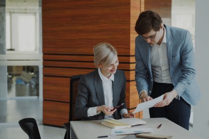 Two colleagues discussing documents at an office desk.; low-cost liability insurance