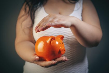 Hands protectively holding an orange piggy bank.; income protection insurance