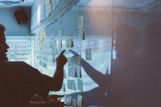 person pointing white paper on wall; AI business planning