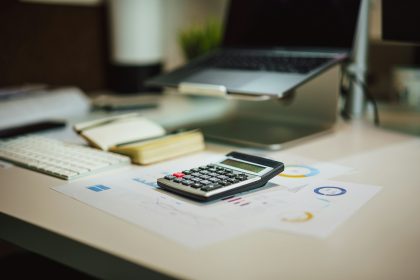 a calculator sitting on top of a table next to a laptop; cloud accounting software