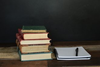 pile of books beside white printer paper and black ballpoint pen; how to write a case study