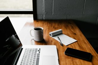 MacBook Pro, white ceramic mug,and black smartphone on table; qualified business income deduction