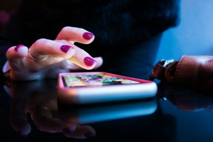 person using black smartphone with gray and pink case; budget expense tracking apps