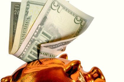 Us dollar bills being inserted into a piggy bank; small business AI spending