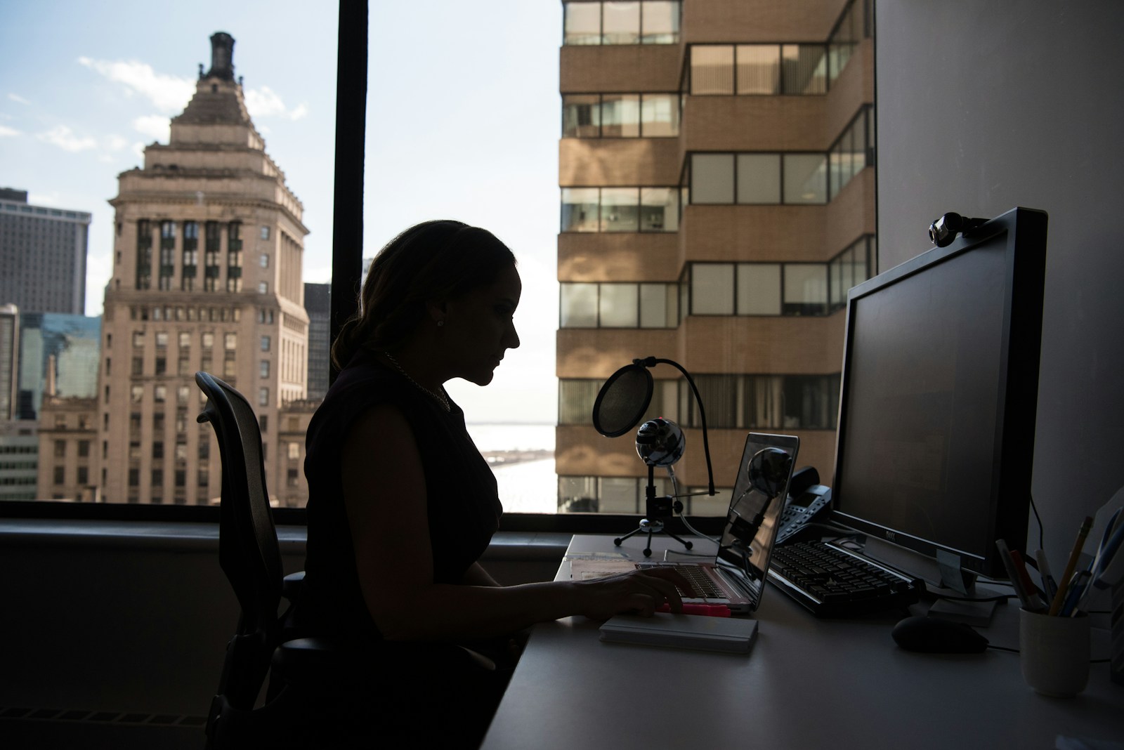 woman sitting in front of desk with computer monitor and keyboard on top; solopreneur